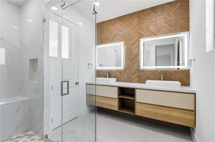 Full bath featuring a marble finish shower, double vanity, and tile patterned floors