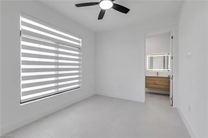 Unfurnished room with a ceiling fan, light tile patterned floors, and baseboards
