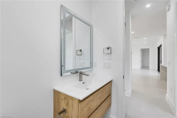 Bathroom with vanity, tile patterned floors, recessed lighting, and baseboards
