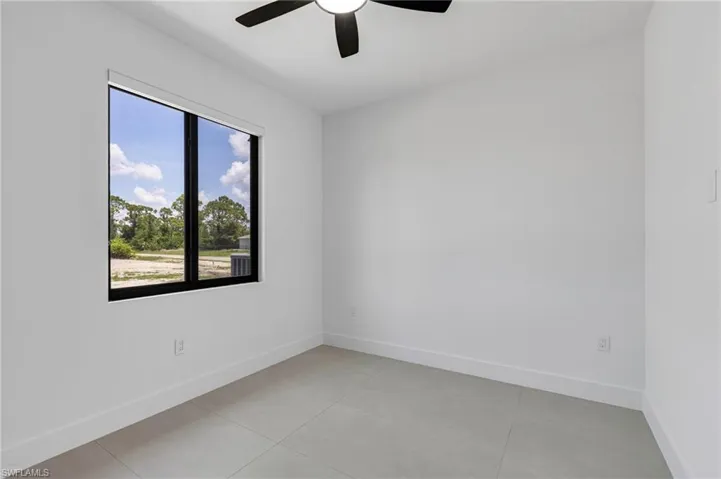 Spare room with a ceiling fan, light tile patterned floors, and baseboards