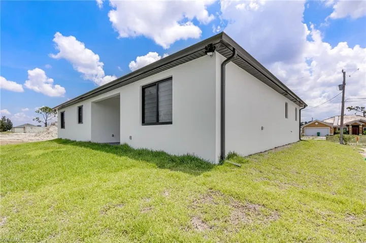 View of side of home featuring stucco siding and a lawn