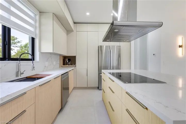 Kitchen featuring island exhaust hood, appliances with stainless steel finishes, a sink, modern cabinets, and backsplash