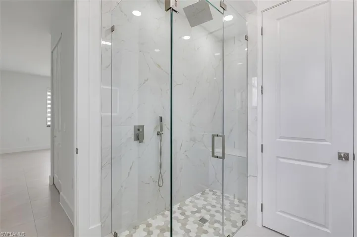 Bathroom with a marble finish shower and tile patterned flooring