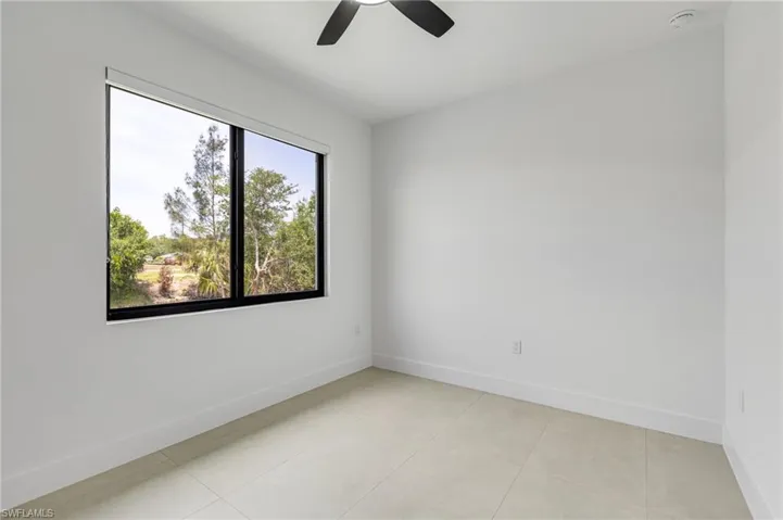 Spare room with ceiling fan, baseboards, a smoke detector, and light tile patterned floors