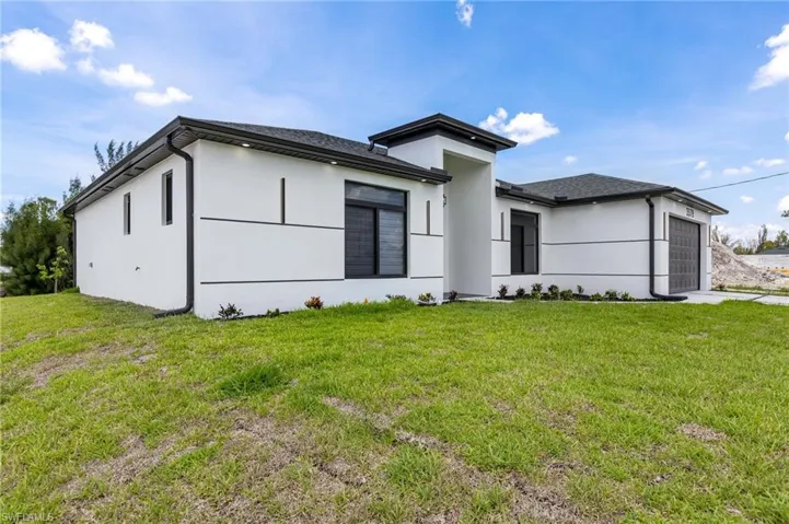 View of front of property with a garage, a front yard, and stucco siding