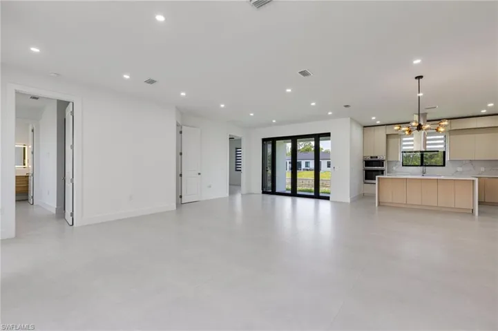 Unfurnished living room with a sink, recessed lighting, a chandelier, and baseboards