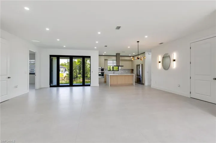 Unfurnished living room featuring recessed lighting, a chandelier, and baseboards