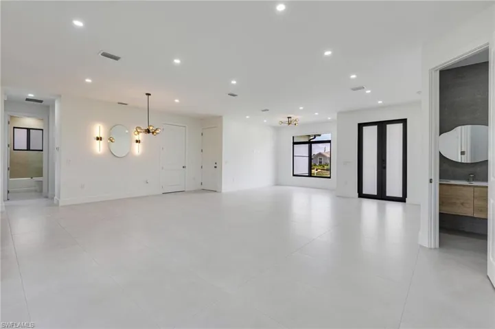 Unfurnished living room with a chandelier, recessed lighting, light tile patterned floors, and baseboards