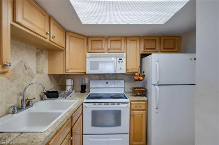 Kitchen featuring white appliances, light countertops, and decorative backsplash
