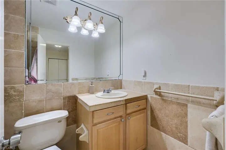 Bathroom featuring tile walls, vanity, and a wainscoted wall