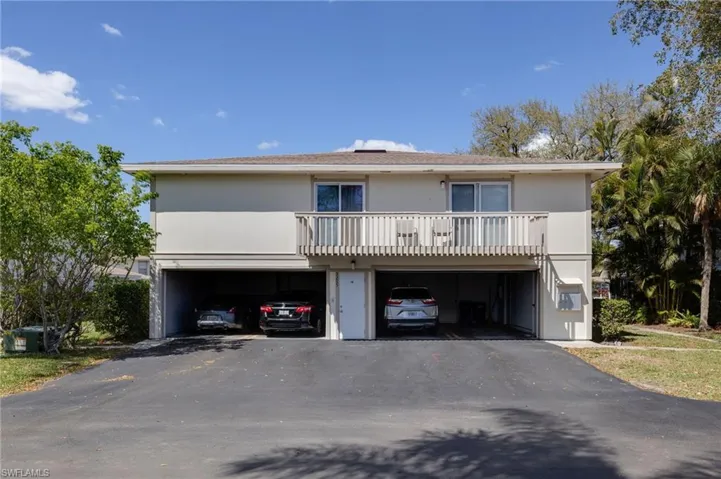 View of front of property with a balcony and asphalt driveway