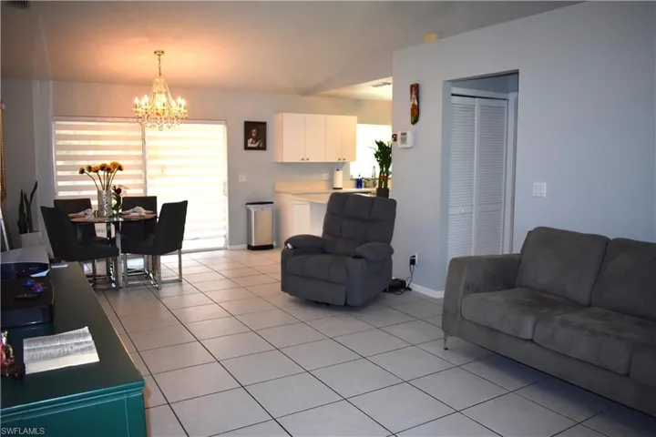 Living room with an inviting chandelier, vaulted ceiling, and light tile floors