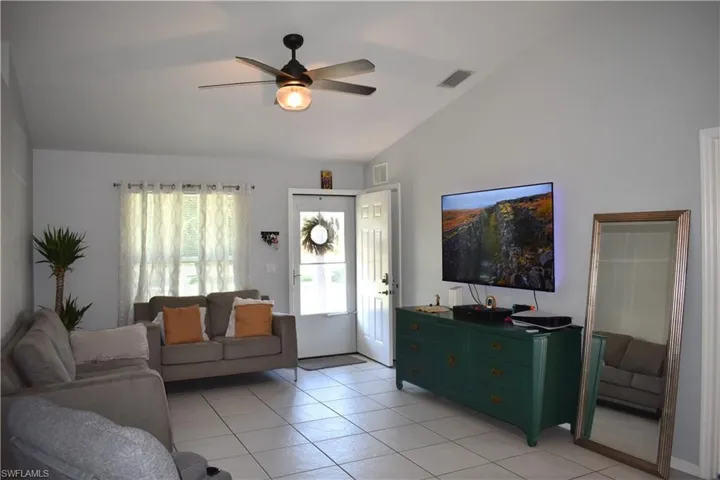 Tiled living room with vaulted ceiling and ceiling fan