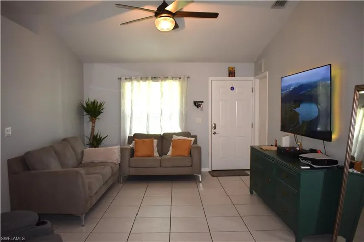 Living room featuring vaulted ceiling, ceiling fan, and light tile floors