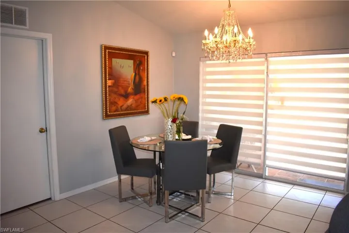 Dining space featuring a notable chandelier, vaulted ceiling, and light tile floors