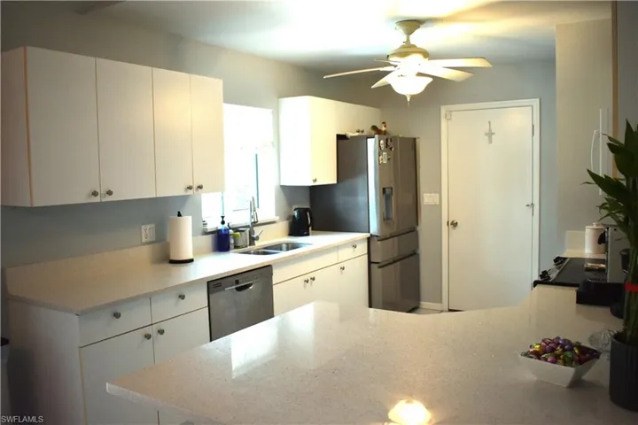 Kitchen featuring appliances with stainless steel finishes, white cabinetry, sink, and ceiling fan