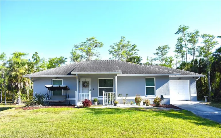 Ranch-style house featuring a garage, a front lawn, and a porch
