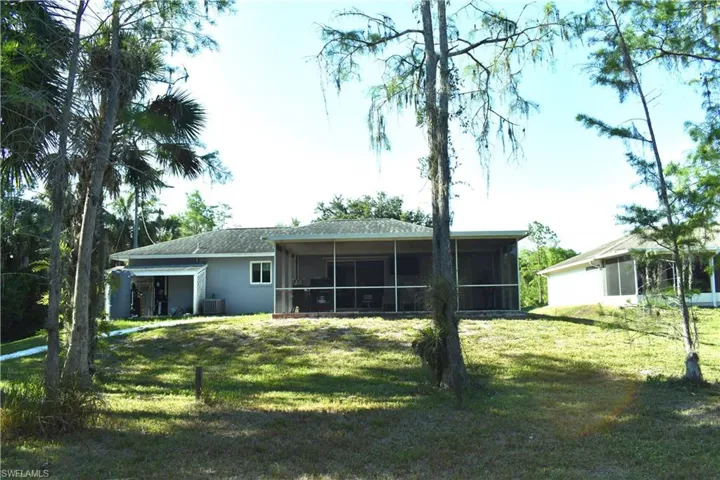 Back of property with a yard, a sunroom, and central AC