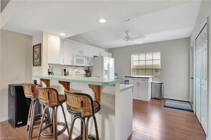 Kitchen featuring white cabinets, light countertops, a peninsula, a breakfast bar area, and light wood-style floors