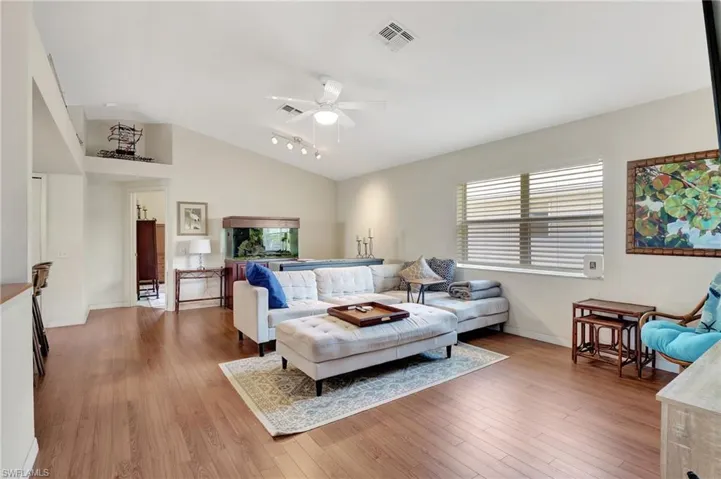 Living room featuring light wood-style floors, lofted ceiling, ceiling fan, and track lighting