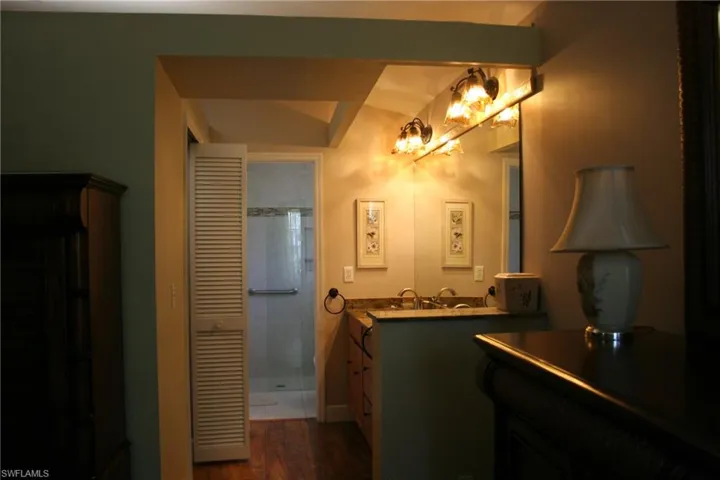 Full bathroom with a stall shower, wood finished floors, vanity, baseboards, and a chandelier