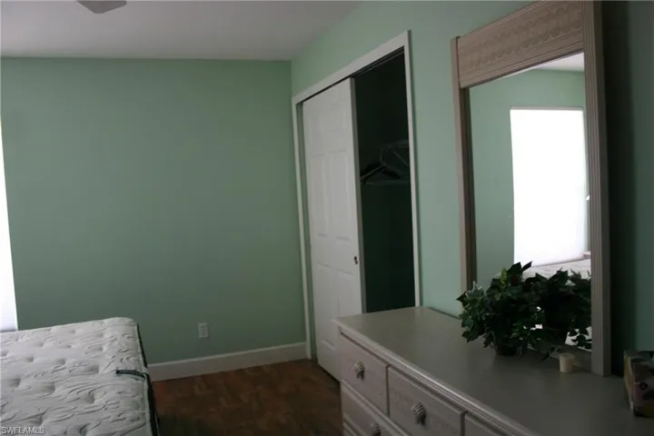 Bedroom with baseboards, a closet, and dark wood-type flooring