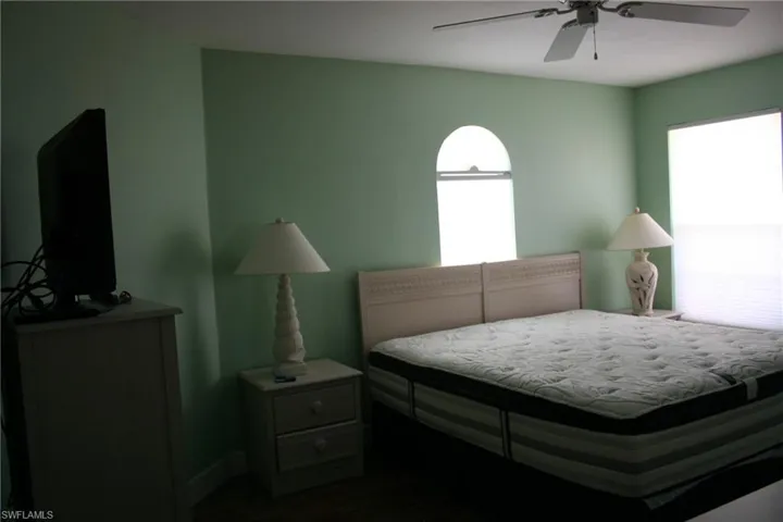 Bedroom featuring dark wood-type flooring, a ceiling fan, and baseboards