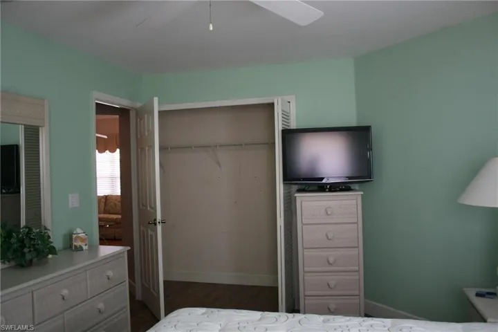 Bedroom featuring dark wood-style flooring, a ceiling fan, and baseboards