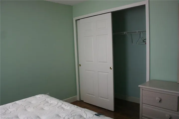 Bedroom featuring baseboards, dark wood finished floors, and a closet