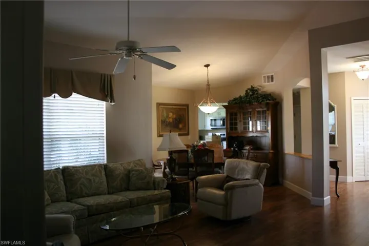 Living area with ceiling fan, arched walkways, baseboards, wood finished floors, and visible vents