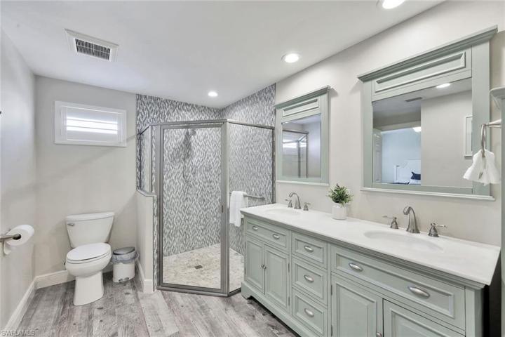 Guest bathroom #1 with double vanity, coastal mirrors, and walk-in shower with beautiful mosaic tile