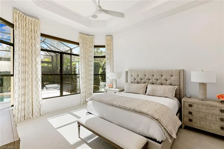 Bedroom featuring a sunroom, a tray ceiling, crown molding, ceiling fan, and carpet flooring