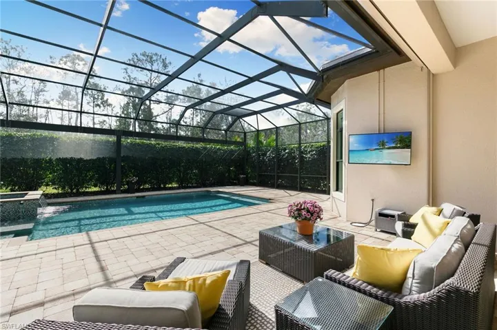 Relaxing pool / spa featuring a patio area, outdoor lounge area, a sunroom, and glass enclosure