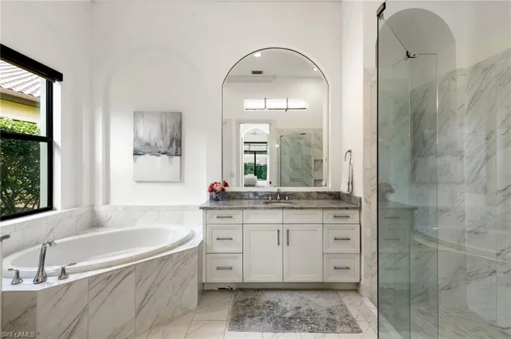 Full bath featuring vanity, a marble finish shower, and a garden tub