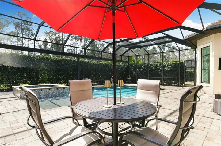 Combined pool / hot tub with a patio, glass enclosure, a sunroom, and outdoor dining area