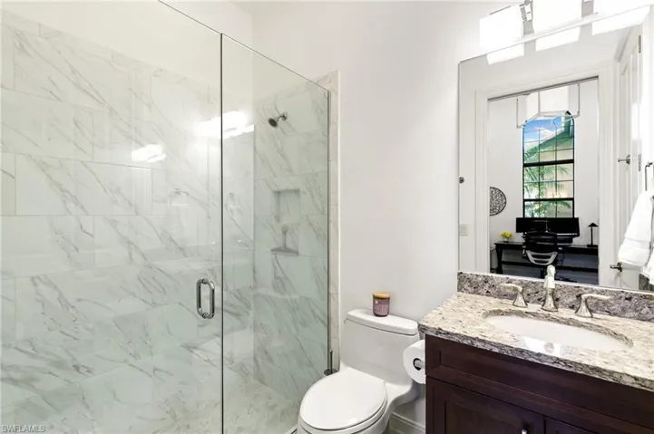 Bathroom with vanity and a marble finish shower