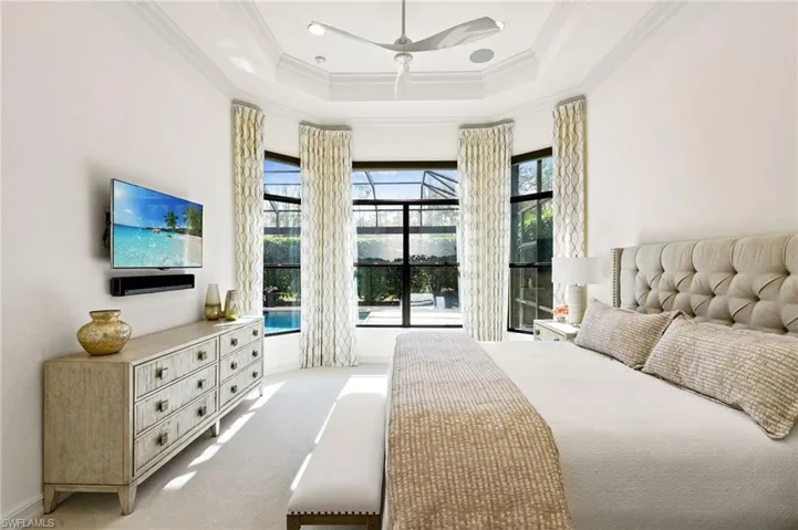 Bedroom featuring a tray ceiling, ceiling fan, ornamental molding, and carpet flooring