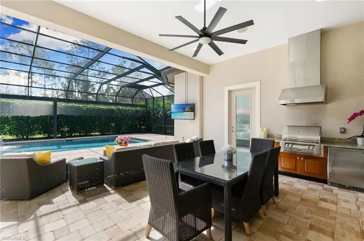 View of patio with an outdoor pool, a lanai, a sunroom, an outdoor kitchen / dining area, and a ceiling fan