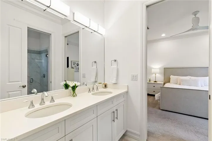Bathroom featuring double vanity, ornamental molding, ensuite bathroom, light carpet, and a marble finish shower