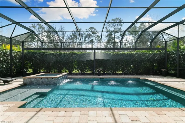 Combined pool / hot tub featuring a sunroom, glass enclosure, and a patio area