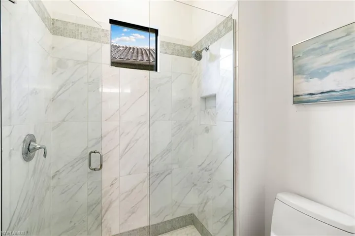 Full bathroom featuring toilet and a marble finish shower