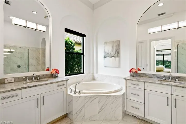 Full bathroom featuring a marble finish shower, two vanities, a garden tub, and recessed lighting