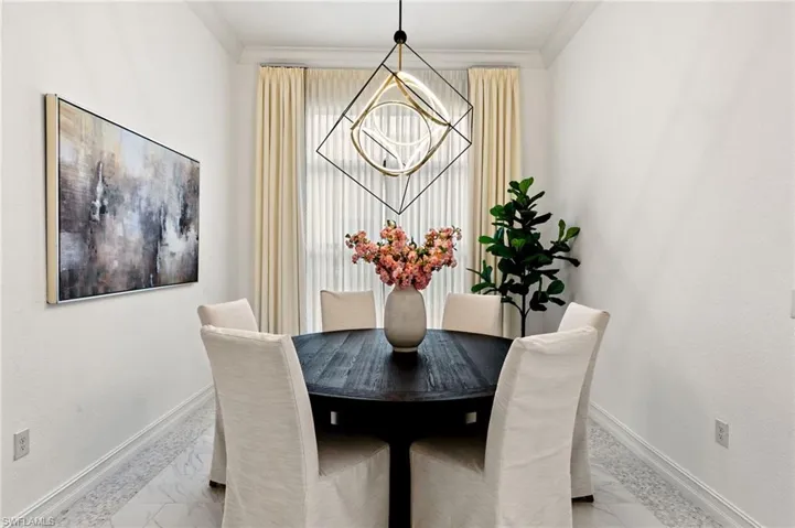 Dining area with crown molding, hanging lights, and light marble finish flooring