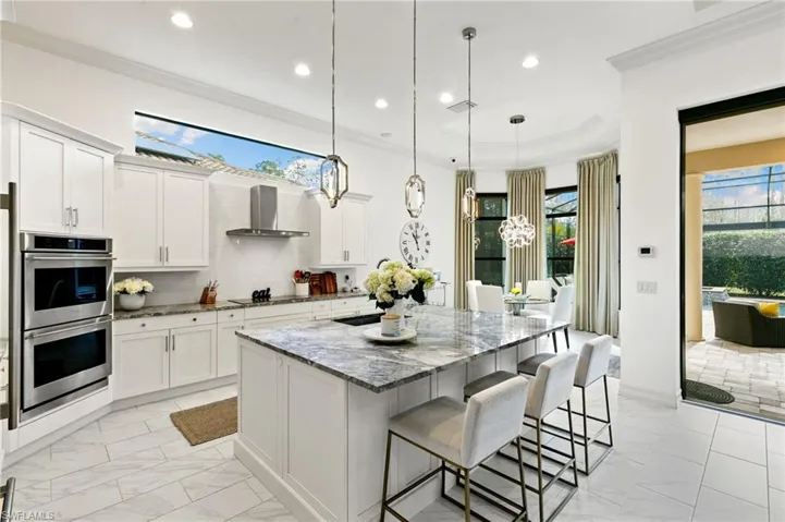 Kitchen with dark stone countertops, a breakfast bar, white cabinets, a kitchen island, and double oven