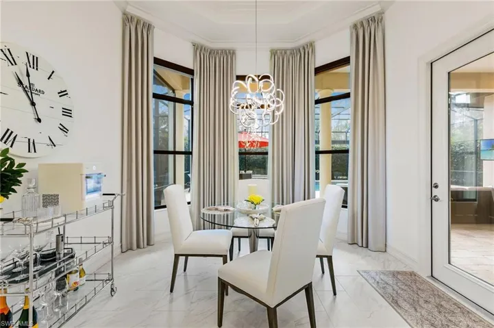 Dining area with ornamental molding, light marble finish floors, suspended lighting, plenty of natural light, and a tray ceiling