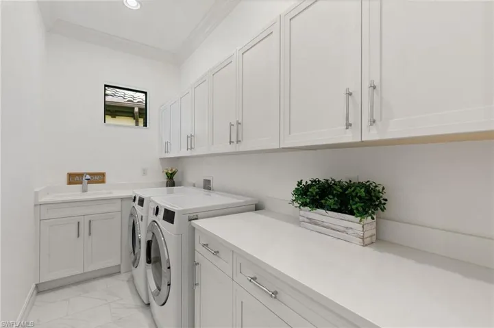 Laundry room with cabinet space, separate washer and dryer, light marble finish floors, and ornamental molding