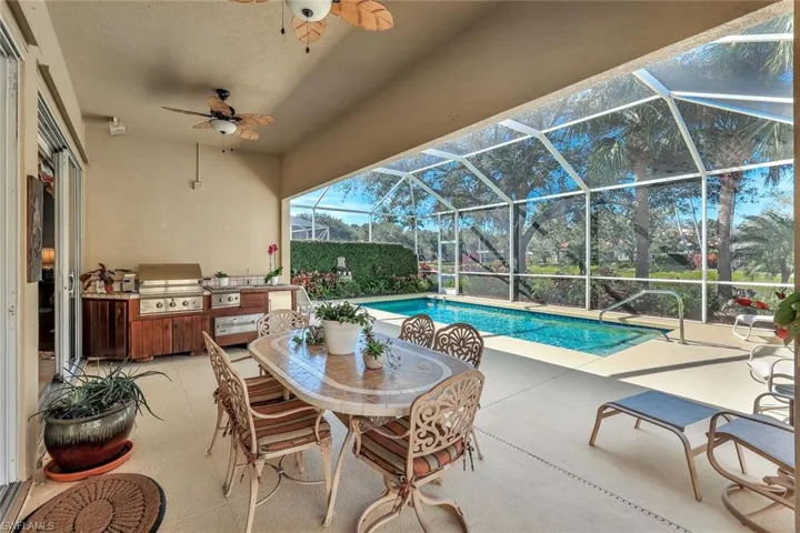 View of swimming pool featuring a patio area, grilling area, glass enclosure, and an outdoor kitchen