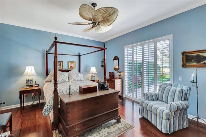 Bedroom with ceiling fan, ornamental molding, and dark engineered wood flooring