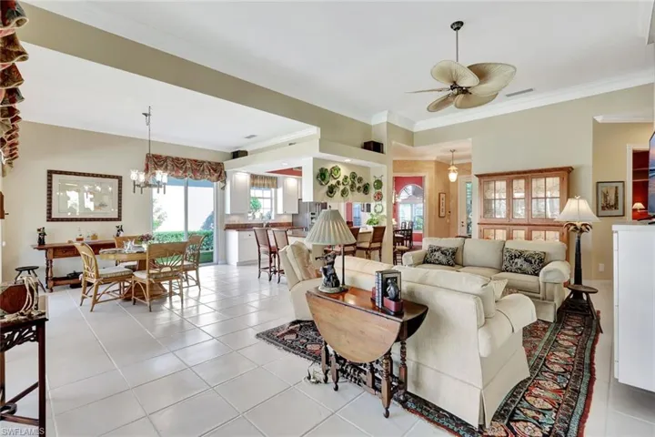 Tiled living room with crown molding and ceiling fan with notable chandelier