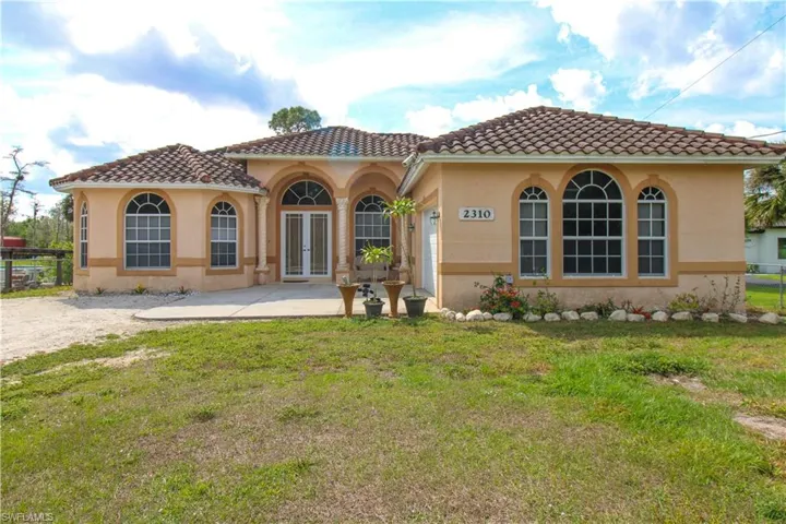 Back of property with french doors, stucco siding, a lawn, fence, and a tiled roof